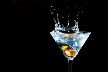 Olive splashing into a martini glass