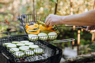 Male chef preparing fresh grilled vegetables, zucchini, peppers on the grill, outdoor barbecue in the backyard in the park. Food photography.