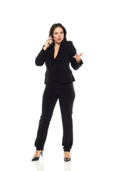 Nervous business woman standing in the white studio and talking on mobile phone.