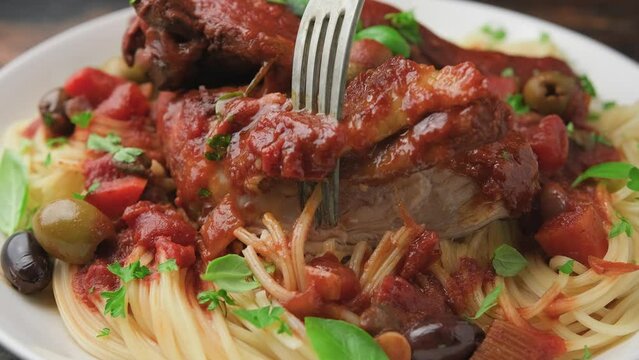 Eating Cacciatore Chicken with spaghetti, vegetables, olives and tomatoes