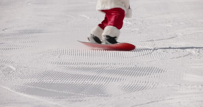 Santa Claus professional snowboarder skiing in resort. Cheerful snowboarder having fun snowboarding winter day in snowy mountains. Winter extreme cheerful sports activities. Active rest in mountains