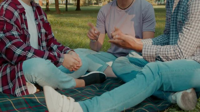 Closeup-of united deaf family and adorable teenage daughter with hearing loss communicating with sign language, sharing and bonding while spending leisure in public park