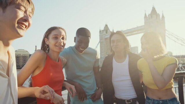 Group of teenagers friends spending time in the main areas of London as the tower bridge. Concept about generation z and friendship
