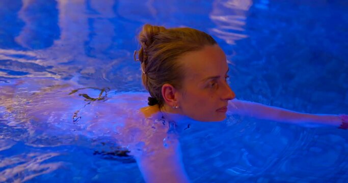 Girl relaxing In the pool at night time.
