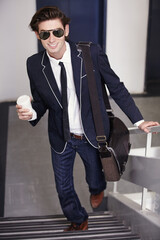 Happy, businessman and walking on stairs with coffee cup in office, fashion or graduate internship...