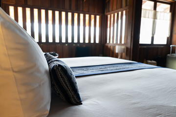Modern White bed and dark blue pillow combination of vintage wooden bedroom Asian style.