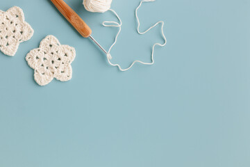 The white crocheted stars with a hook on a blue background with copy space.