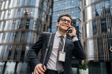The deadline is coming, A confident Man is smiling in a business suit with glasses. A businessman phone calls a colleague in a hurry to meet at work in the office for a meeting.