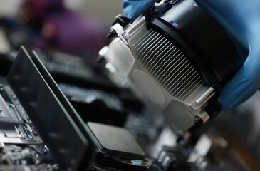 Close-up of person install cooler fan with copper tubes on computer processor, connect parts. Computer motherboard fixation. Technology, repair concept
