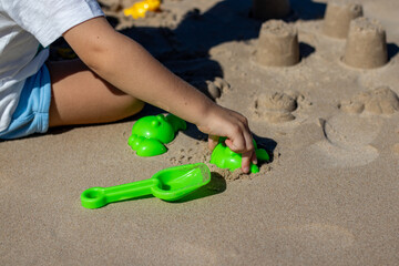 Fototapeta na wymiar Child playing on the beach. Play in the sand during the holidays. fun with sand and beach toys.