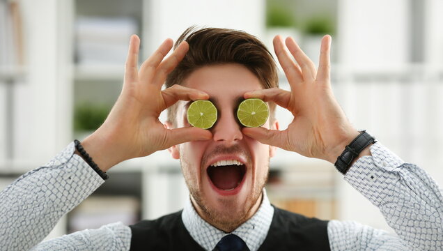 Portrait of guy put lime fruit slices on eyes instead of glasses, goofing around, funny man. Choose healthy lifestyle, add vitamins. Be healthy concept