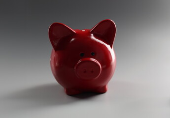 Close-up of red piggybank container on grey surface, thing to save money, ceramic animal. Finance, saveup for future, success, economy, investment concept