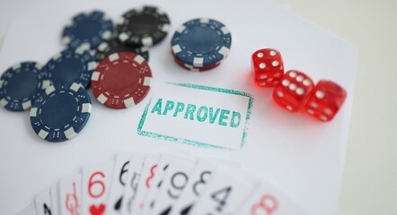 Close-up of stamp approved standing near playing cards and chips in casino with dice. Addiction, player, entertainment, winner, game, fun, luck concept