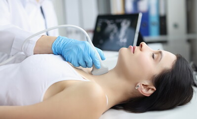 Obraz na płótnie Canvas Portrait of ultrasound scanning diagnostic of woman thyroid gland in clinic, doctor runs ultrasound sensor over patients neck with gel. Diagnostics concept