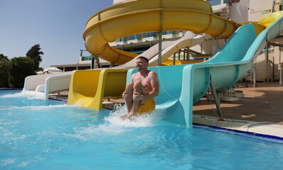 Portrait of middle aged man having fun, sliding at water park, summer vacation. Person laugh, enjoy...