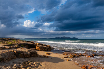 Fototapeta na wymiar High waves hitting the shore and splashing over the rocks on a beautiful cloudy day.