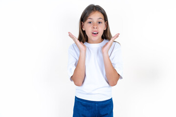 Surprised terrified Beautiful kid girl wearing white T-shirt Gestures with uncertainty, stares at...