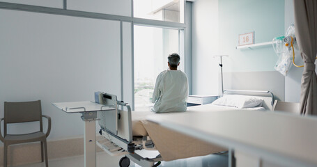 Back, healthcare and a woman on a hospital bed by the window in recovery or waiting for a visit....