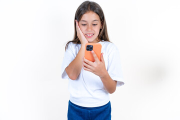 Beautiful kid girl wearing white T-shirt holding in hands cell reading sms using new app 5g