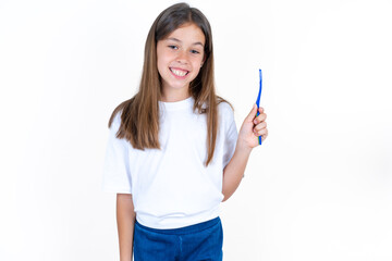 Beautiful kid girl wearing white T-shirt holding a toothbrush and smiling. Dental healthcare concept.
