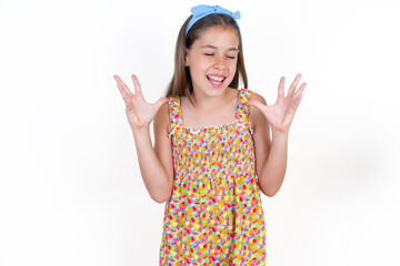 Crazy outraged Beautiful kid girl wearing floral dress screams loudly and gestures angrily yells...