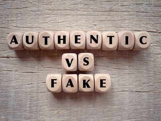 Business and financial issue concept. AUTHENTIC VS FAKE written on wooden blocks. With blurred...