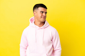 Young handsome man over isolated yellow background having doubts while looking side