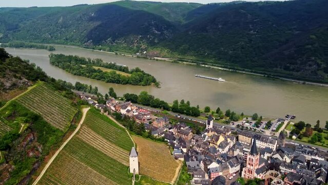 Bacharach german town in middle Rhine Valley with its timbered medieval houses and vineyards overlooking waterway transportation barge ships. Aerial