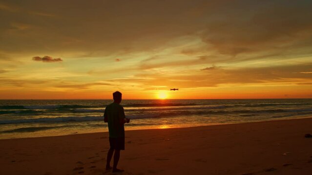.A man uses a drone to take photos at the beach..Amazing Golden yellow sky during sunset..smooth wave hit on the beach..stunning reflection of colorful cloud in sweet sky on sea surfect.sky texture.