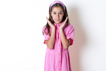 Surprised terrified Beautiful kid girl wearing pink dress Gestures with uncertainty, stares at...