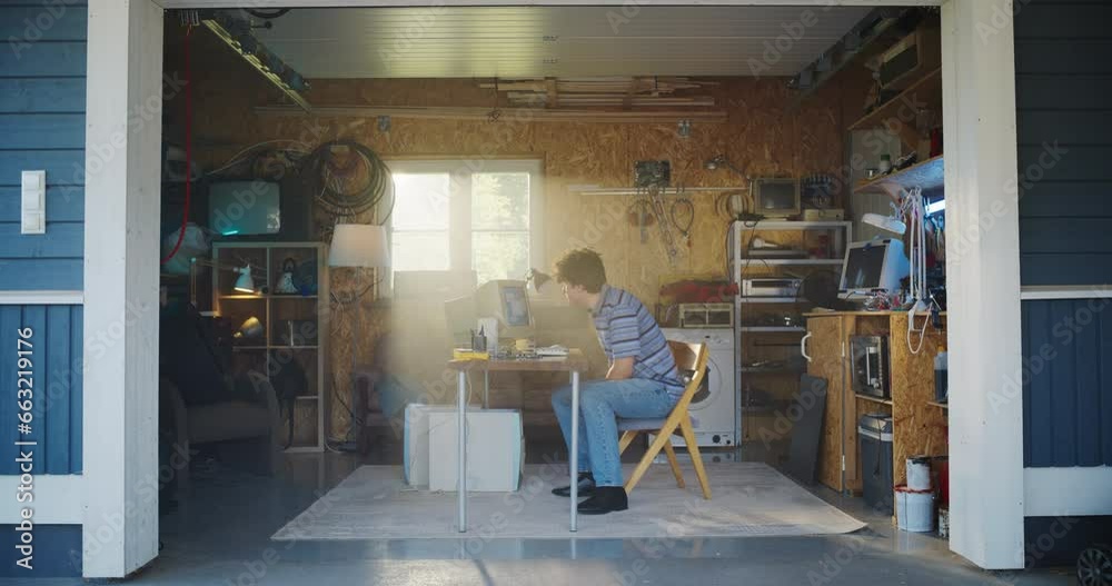 Leinwandbilder caucasian male software engineer entering retro garage and sitting at his work desk with old desktop