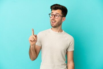 Fototapeta premium Young caucasian handsome man isolated on blue background intending to realizes the solution while lifting a finger up