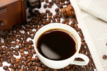Black coffee and coffee beans on newspaper