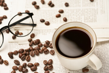 Black coffee and coffee beans on newspaper