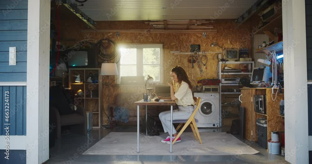 Leinwandbilder hispanic female software engineer programming on laptop computer in garage at home. focused young wo