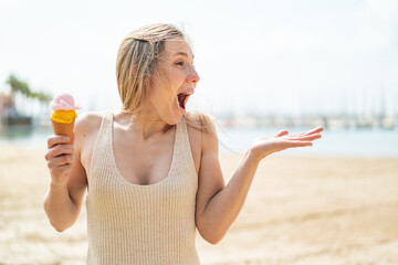 Young blonde woman with a cornet ice cream at outdoors with surprise facial expression