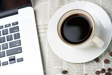 Black coffee and coffee beans on newspaper