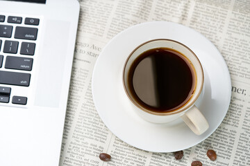 Black coffee and coffee beans on newspaper