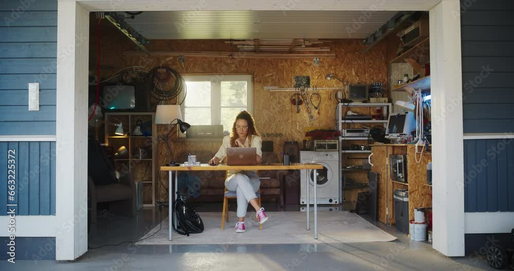 Poster hispanic female software developer coding on laptop computer in garage at home. focused young woman 