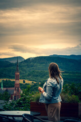 Beautiful dark blond woman in brown dress and blue jeans jacket on view point in Walbrzych, Poland,...