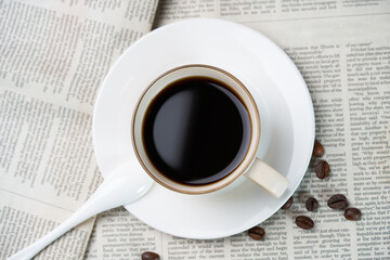 Black coffee and coffee beans on newspaper