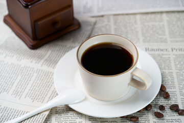 Black coffee and coffee beans on newspaper