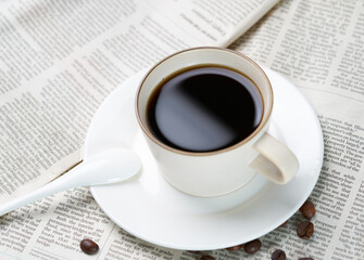 Black coffee and coffee beans on newspaper