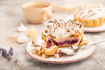 Two tartlets with meringue cream and cup of coffee on brown concrete, side view, selective focus.