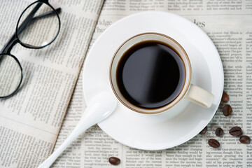 Black coffee and coffee beans on newspaper
