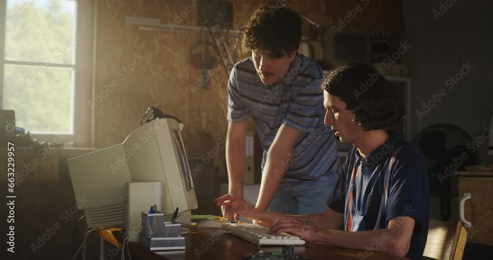 Poster two caucasian male tech startup founders using old desktop computer in retro garage. software develo