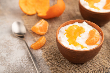 Grained cottage cheese with tangerine jam on brown concrete, side view, selective focus.
