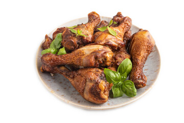 Smoked chicken legs on a ceramic plate isolated on white background. Side view, close up.