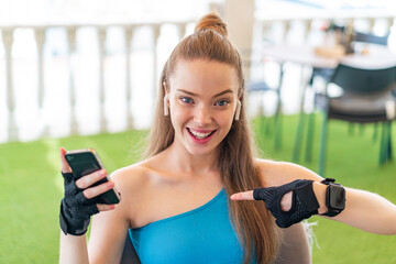 Young pretty sport girl using mobile phone at outdoors with surprise facial expression