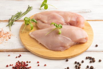 Raw chicken breast on white wooden background. Side view, close up.